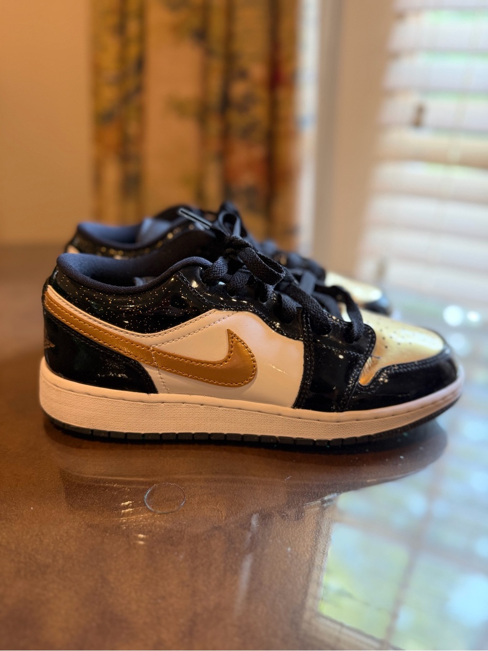 Jordan 1 low gold/black sneakers with white accents and gold Nike swoosh
